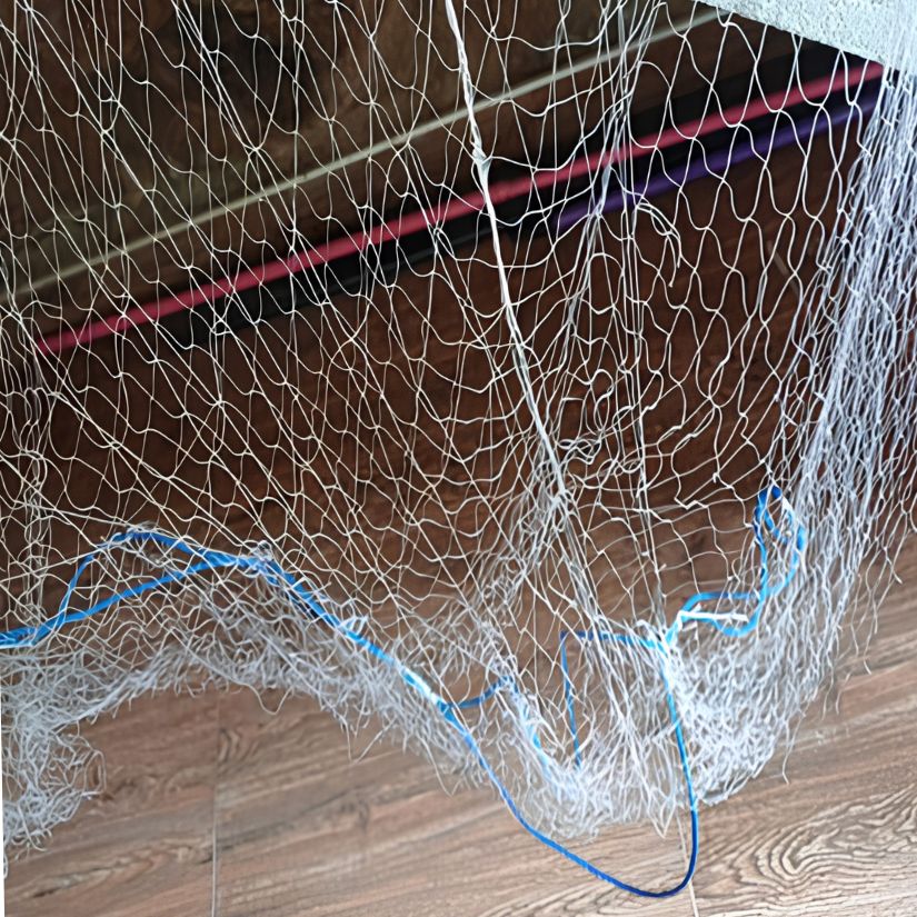 Close-up of a tangled fishing net with blue rope on a wooden floor.